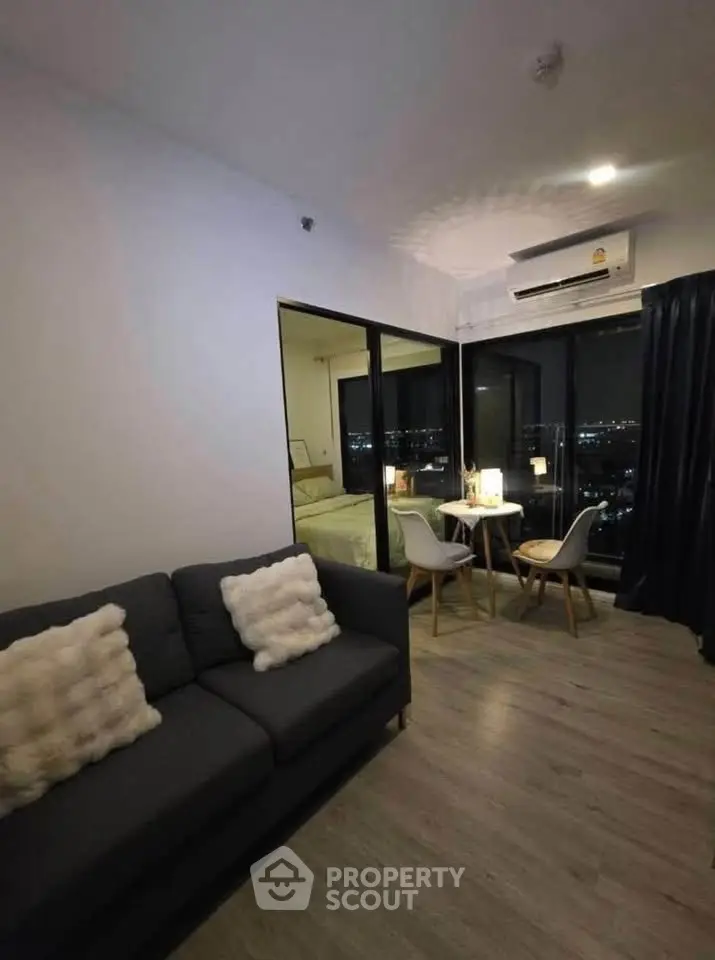 Modern living room with city view, cozy seating, and dining area in a stylish apartment.