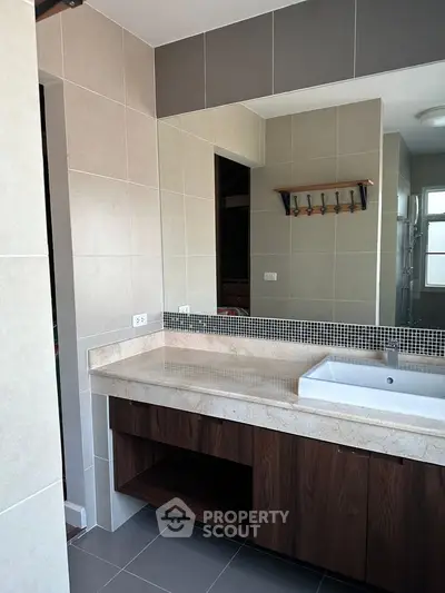 Modern bathroom with sleek vanity and large mirror in contemporary home.