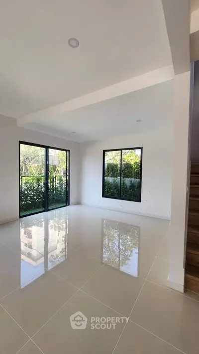 Spacious modern living room with large windows and glossy tiled floor