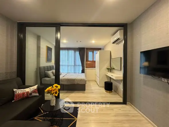 Modern studio apartment with stylish living area and cozy bedroom, featuring sleek furniture and natural light.