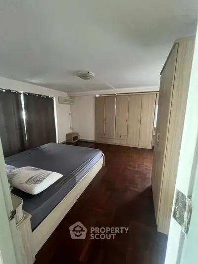 Spacious bedroom with wooden flooring and large wardrobe in modern apartment