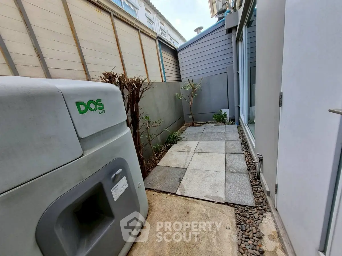 Compact outdoor space with modern utility unit and small garden area.