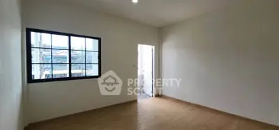 Spacious empty room with wooden flooring and large window, ideal for customization.
