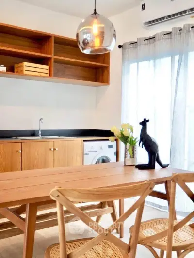 Charming kitchen with wooden cabinets, dining table, and washing machine, perfect for modern living.