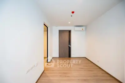 Spacious empty room with wooden flooring and air conditioning, ready for customization.