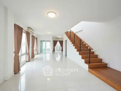 Spacious modern living room with elegant staircase and large windows