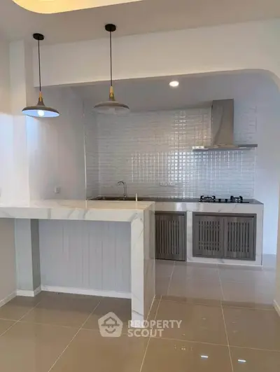 Modern kitchen with sleek design, featuring a gas stove and stylish lighting, perfect for culinary enthusiasts.