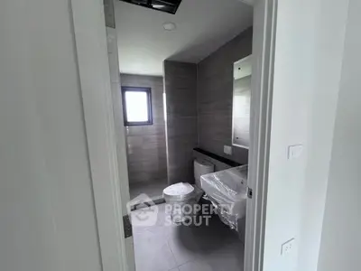 Modern bathroom with sleek design and natural light, featuring a toilet and sink.