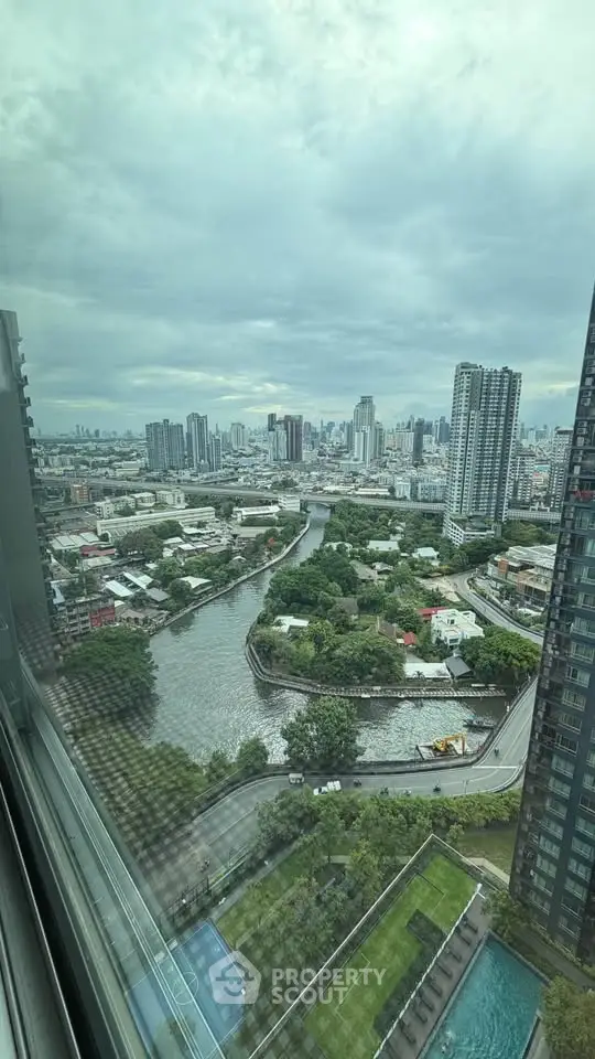 Stunning cityscape view from high-rise apartment window overlooking river and skyline.