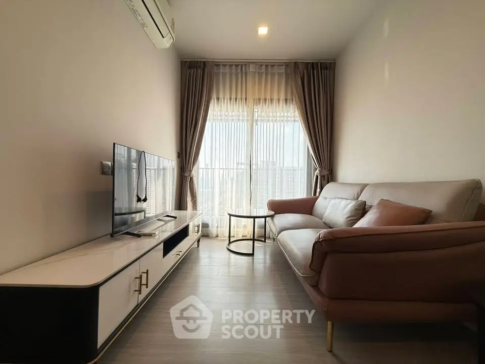 Modern living room with sleek furniture and large window offering natural light.