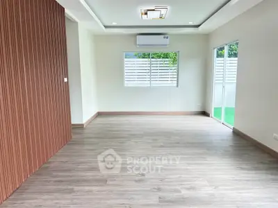 Spacious modern living room with wooden flooring and large windows for natural light.