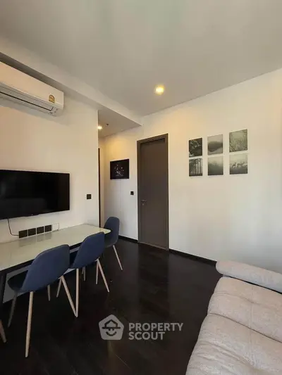 Modern living room with sleek design, featuring a wall-mounted TV, stylish dining area, and cozy seating.