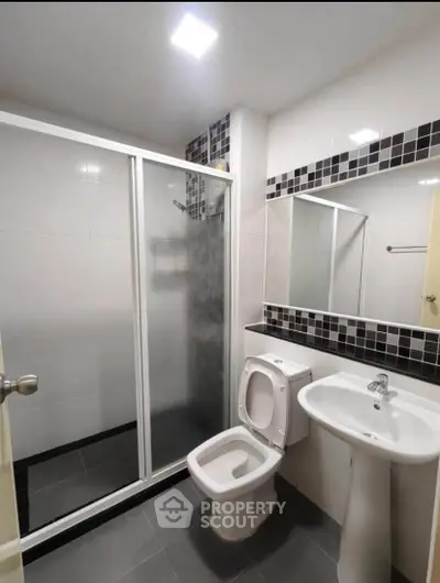Modern bathroom with sleek shower and stylish black and white tiles.