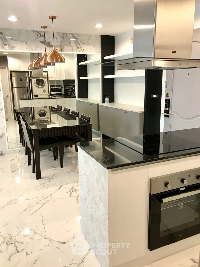 Luxurious modern kitchen with marble flooring and sleek appliances, featuring an open layout and elegant dining area.