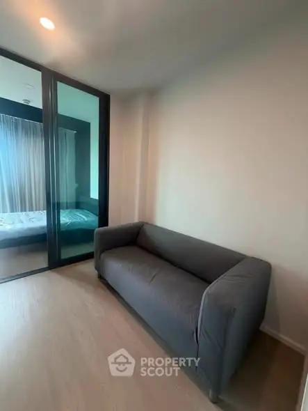 Modern apartment with cozy sofa and glass partition leading to bedroom.