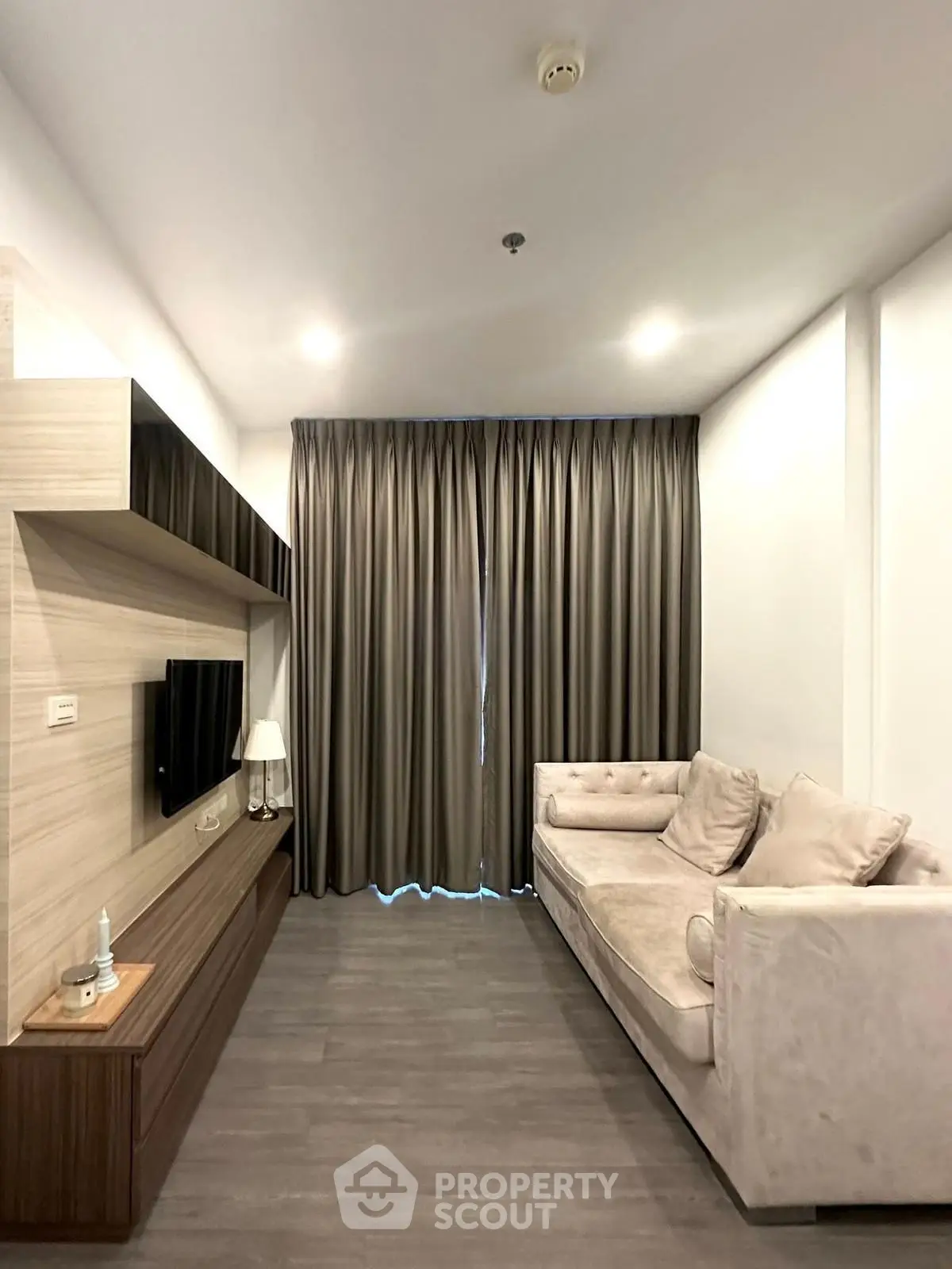 Modern living room with elegant sofa and wall-mounted TV in a cozy apartment.