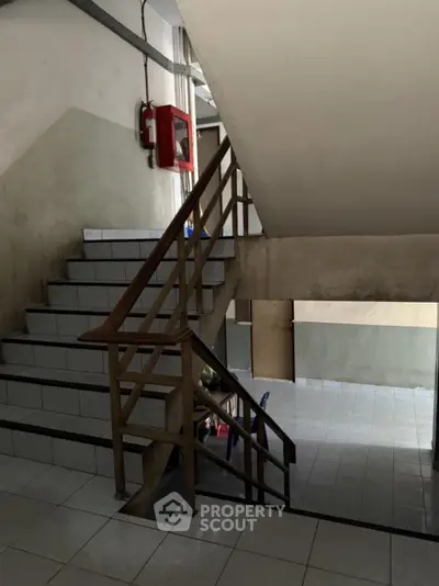 Staircase in a residential building with tiled steps and wooden railing