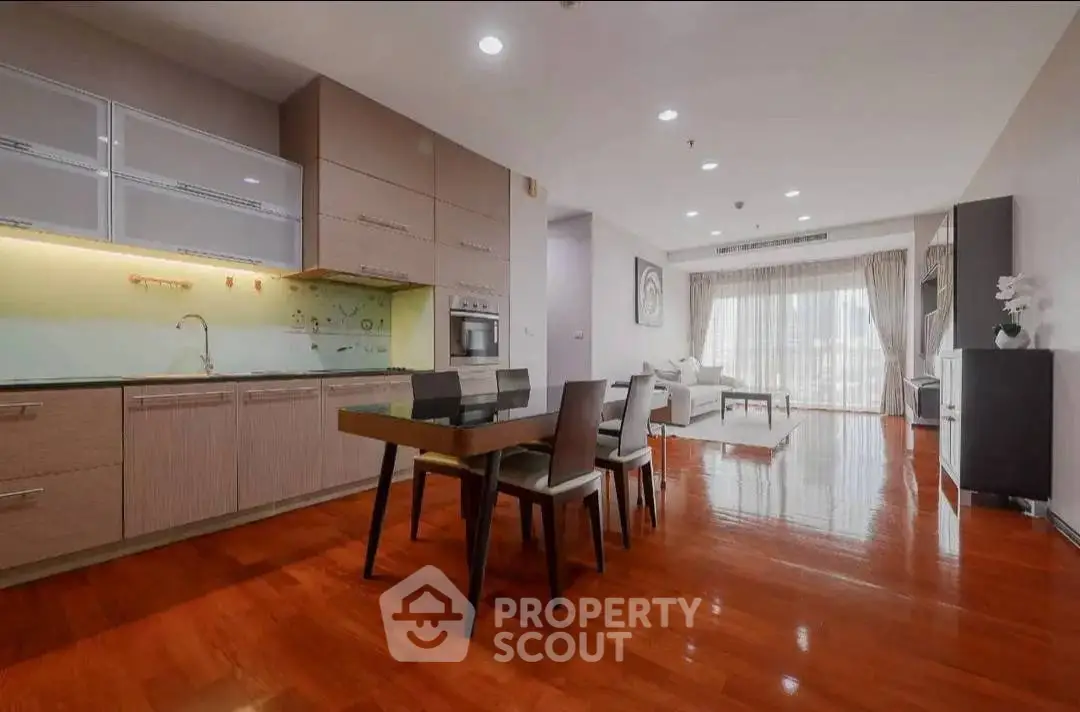 Spacious open-layout kitchen and living room with elegant wooden flooring and modern furniture.