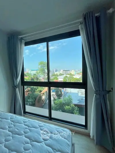 Bright bedroom with large window offering stunning city view and natural light.