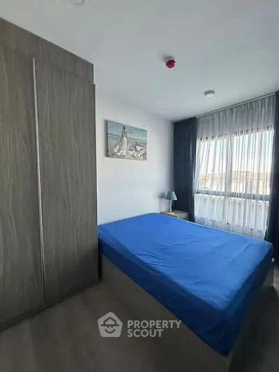 Modern bedroom with large window and stylish decor in a contemporary apartment.