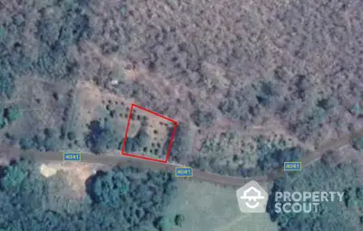 Aerial view of a plot of land with surrounding greenery and road access, ideal for development.