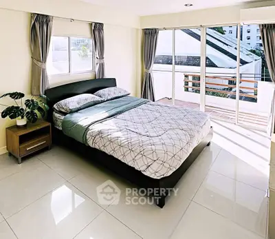 Spacious bedroom with large windows and balcony access, offering abundant natural light and modern decor.