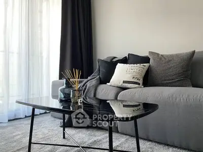 Modern living room with sleek gray sofa and stylish black coffee table.