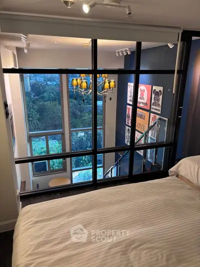Modern bedroom with glass wall overlooking stylish living area and scenic view.