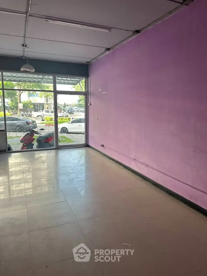 Spacious commercial space with large windows and vibrant purple walls, ideal for retail or office use.
