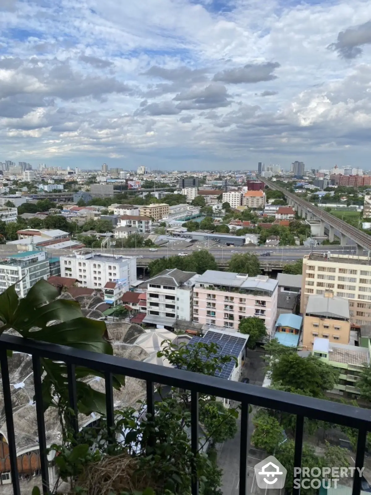 Stunning cityscape view from high-rise balcony with lush greenery and expansive skyline.