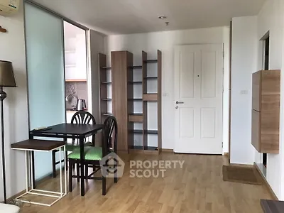 Modern apartment interior with wooden flooring, dining area, and open shelving.
