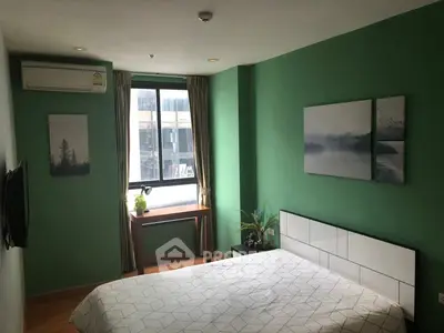 Cozy bedroom with green walls, modern decor, and natural light from large window.