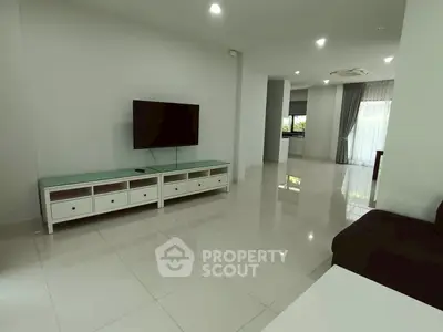 Spacious modern living room with sleek tile flooring and wall-mounted TV, perfect for entertainment.
