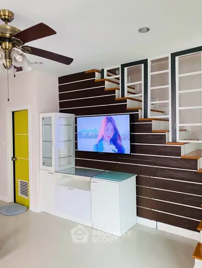 Modern living room with stylish staircase and built-in storage solutions.