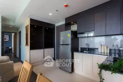 Modern kitchen with sleek cabinetry and stainless steel fridge in open-plan layout.