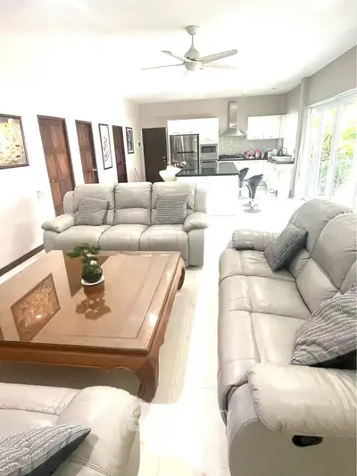 Spacious living room with modern furniture and open kitchen layout, perfect for family gatherings.