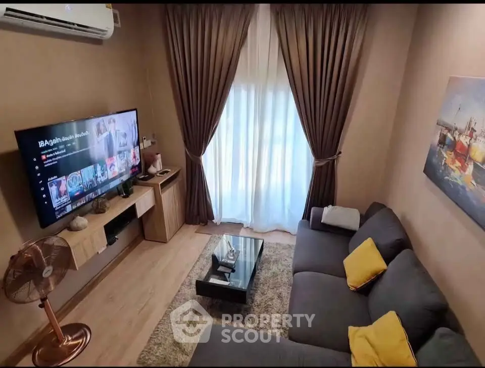 Cozy living room with modern decor, large TV, and plush sofa.