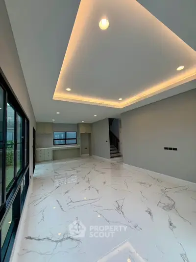 Spacious modern living room with elegant marble flooring and recessed lighting, perfect for luxury living.