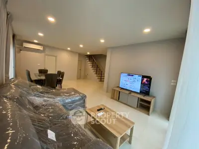 Spacious modern living room with sleek furniture and staircase, perfect for family gatherings.