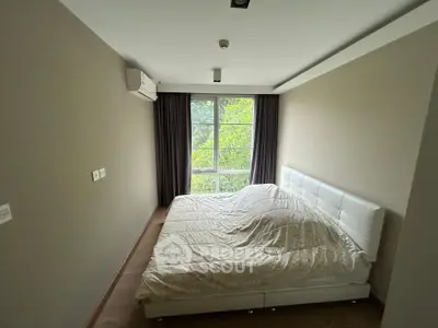 Cozy bedroom with large window and modern decor in a serene setting.