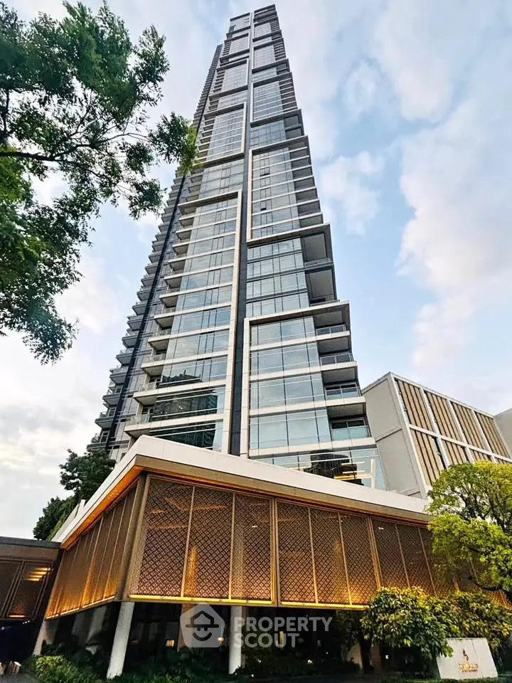 Stunning modern high-rise building with sleek glass facade and lush greenery at the base.