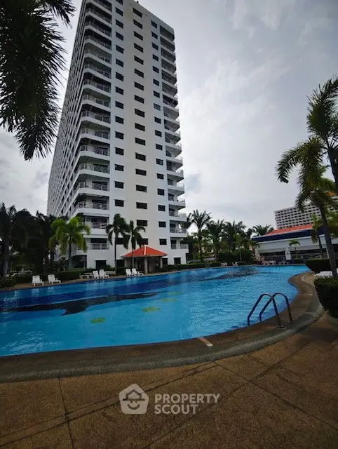 Luxurious high-rise building with a stunning pool and lush palm trees, perfect for resort-style living.