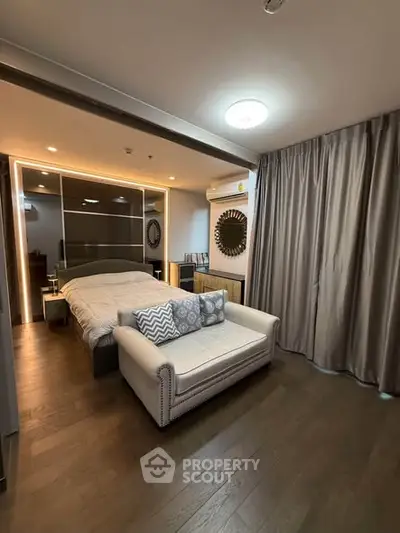 Luxurious bedroom with elegant decor and cozy seating area in modern apartment.