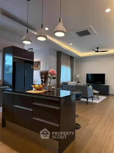Modern open-layout kitchen and living room with stylish lighting and wooden flooring.