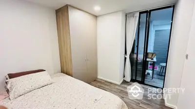 Modern bedroom with cozy decor and sliding glass doors leading to a balcony.