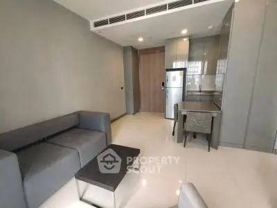 Modern living room with sleek furniture and compact kitchen area.