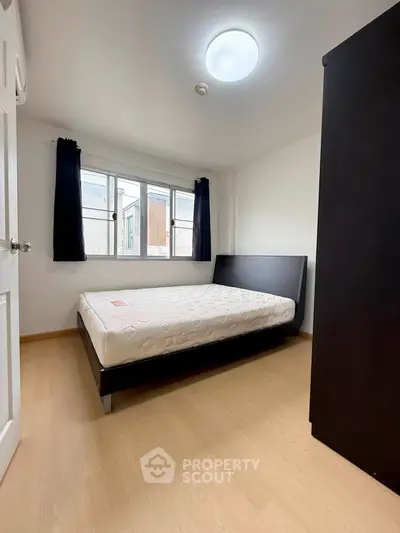 Cozy bedroom with natural light and minimalist design, featuring a comfortable bed and wooden flooring.