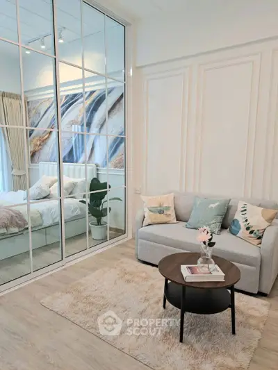 Chic modern living room with cozy sofa and mirrored wall reflecting stylish bedroom.