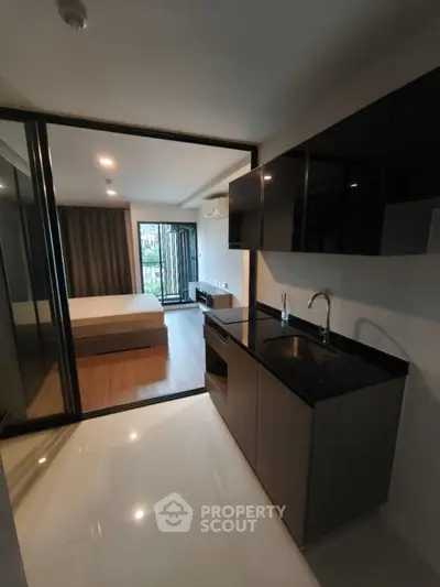 Modern studio apartment with sleek kitchen and cozy bedroom, featuring floor-to-ceiling windows and contemporary design.
