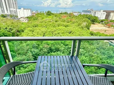 Stunning balcony view with lush greenery and ocean in the distance, perfect for relaxation.